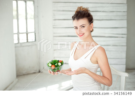 Portrait of a young woman holding a fresh salad Portrait of a young woman holding a fresh salad 34156149