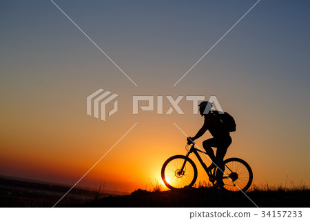 Silhouette of a bike tourist on mountain peak. Silhouette of a bike tourist on mountain peak. 34157233