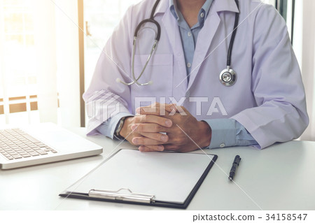 Close up of doctor filling up an history form while consulting p Close up of doctor filling up an history form while consulting p 34158547