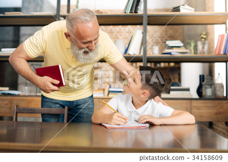 Caring grandfather checking his grandsons progress Caring grandfather checking his grandsons progress 34158609