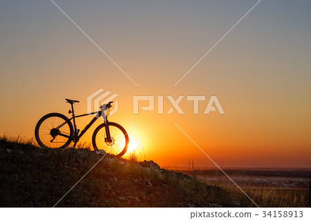 Silhouette of a bike on the hills at sunset. Silhouette of a bike on the hills at sunset. 34158913