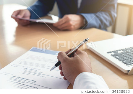 Executive reading a resume during a job interview and businessma Executive reading a resume during a job interview and businessma 34158933