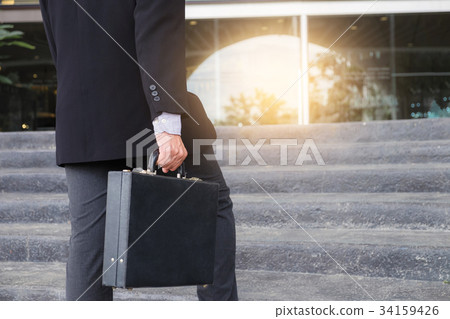 Businessman walking up the stairs and holding a briefcase in han Businessman walking up the stairs and holding a briefcase in han 34159426