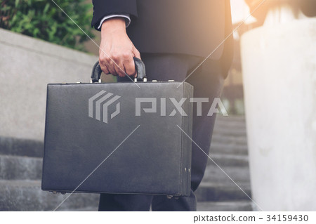Businessman standing and holding a briefcase in hand working wit Businessman standing and holding a briefcase in hand working wit 34159430