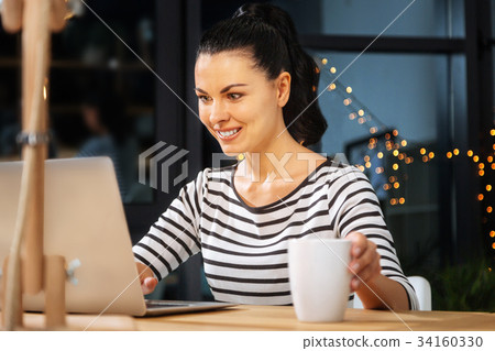 Cheerful pleasant woman putting a cup on the table Cheerful pleasant woman putting a cup on the table 34160330