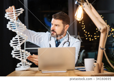 Smart professional researcher studying a DNA model 34160695
