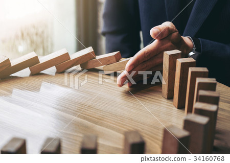 Close up of businessman hand Stopping Falling wooden Dominoes ef 34160768