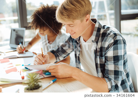 Positive young male student studying with his Positive young male student studying with his 34161604