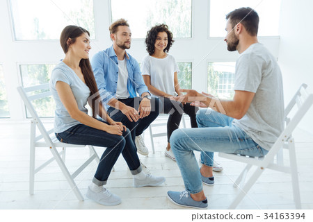 Handsome nice man sitting in front of his group Handsome nice man sitting in front of his group 34163394