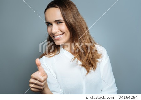 Joyful positive woman showing thumbs up gesture Joyful positive woman showing thumbs up gesture 34164264