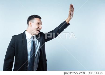 Cheerful nice man holding his hand up 34164438