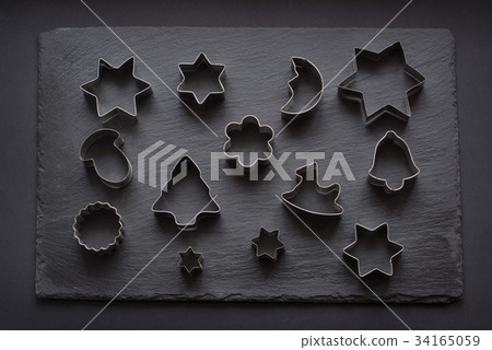 Various Christmas-themed cookie cutters on black. 34165059
