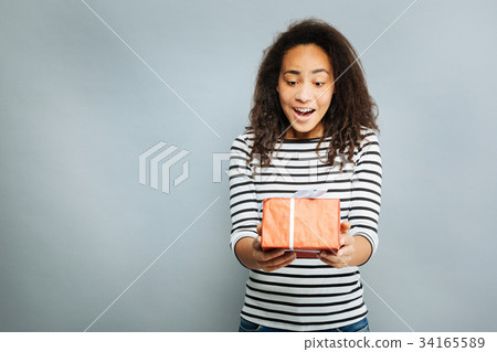 Surprised brunette looking at gift box Surprised brunette looking at gift box 34165589
