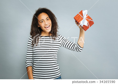Cheerful international girl showing her present 34165590