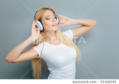 Delighted female person enjoying music Delighted female person enjoying music 34166036