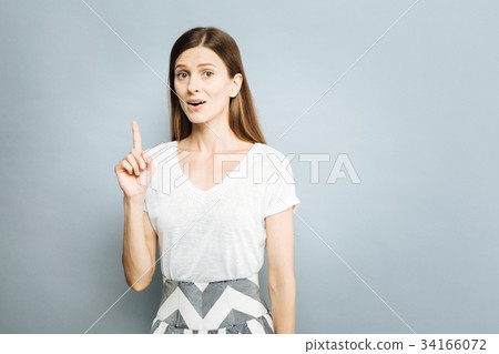 Confused girl raising her forefinger up Confused girl raising her forefinger up 34166072