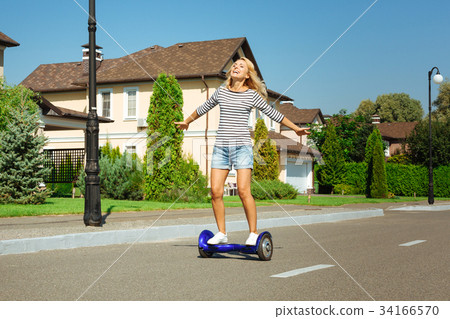 Happy woman riding self-balancing scooter down the 34166570