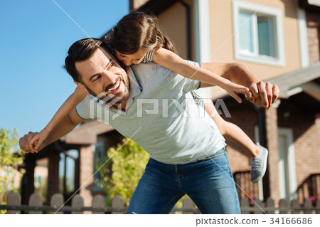 Upbeat father carrying his daughter on back Upbeat father carrying his daughter on back 34166686