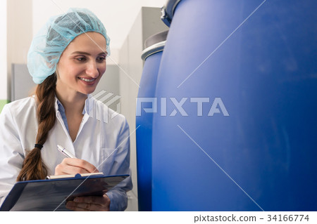 Manufacturing employee writing report during Manufacturing employee writing report during 34166774
