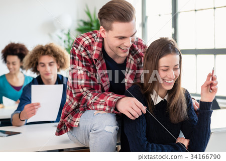 Two cheerful millennial students laughing while 34166790