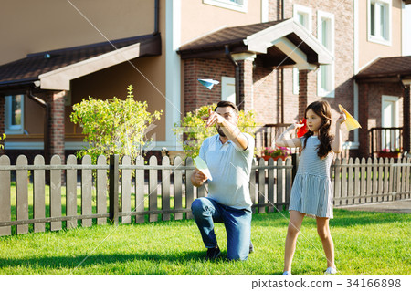 Charming daughter launching paper planes with 34166898