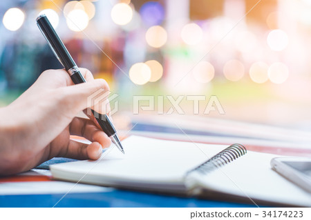 Woman's hand writing on a notebook with a pen Woman's hand writing on a notebook with a pen 34174223