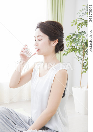 A woman drinking water in a cup A woman drinking water in a cup 34175041