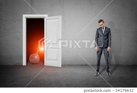 A sad businessman stands with shoulders slumped 34176632