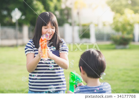 Asian chid Shooting Bubbles from Bubble Gun 34177708