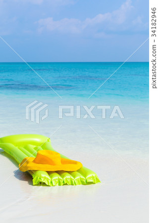 Green airbed ans hat on beach 34182946