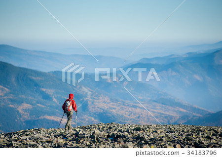 Male backpaker walking on the rocky top of the mountain 34183796