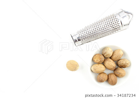 nutmeg seeds in a small white bowl 34187234