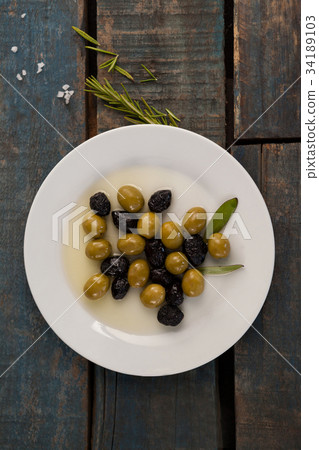 Directly above shot of olives in container by herb 34189103