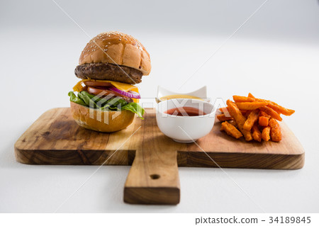 Hamburger by french fries in container on cutting board Hamburger by french fries in container on cutting board 34189845