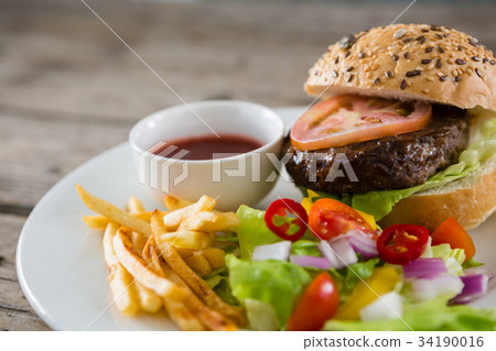 High angle view of hamburger by onion rings with dip and french fries 34190016