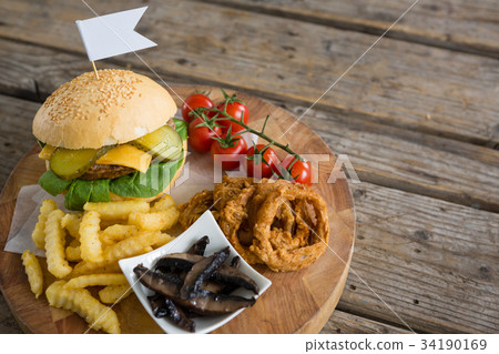 French fries with sauce by burger and onion rings on cutting board 34190169