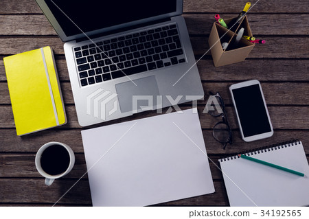 Laptop, diary, spectacles, camera and pen holder on wooden table Laptop, diary, spectacles, camera and pen holder on wooden table 34192565