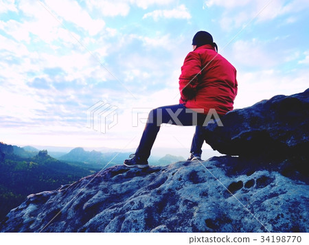 Hiker man take a rest on mountain peak.Tourist sit Hiker man take a rest on mountain peak.Tourist sit 34198770