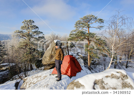 Male climber nearly his tent on the top of rock 34198932