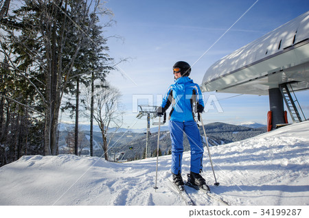 Female skier against ski-lift and winter mountains background 34199287