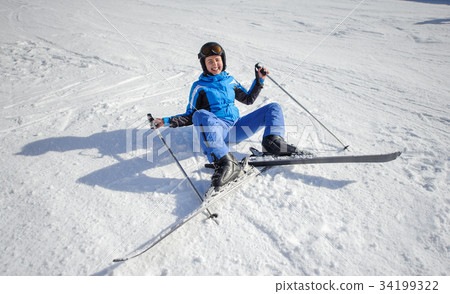 Young female skier after the fall on mountain slope 34199322