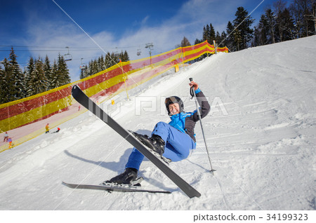 Young female skier after the fall on mountain slope 34199323