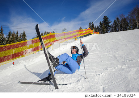Young female skier after the fall on mountain slope 34199324