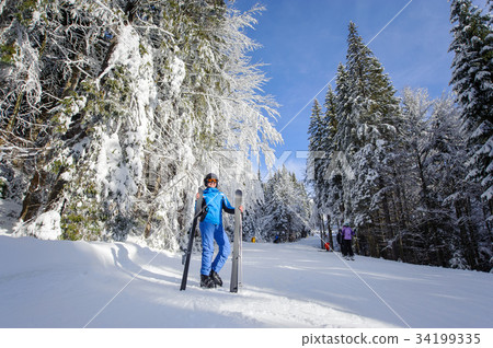 Happy woman skier on a ski slope in the forest Happy woman skier on a ski slope in the forest 34199335