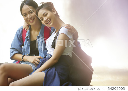 two happy hikers are sitting side by side and arm in arm in the forest. two happy hikers are sitting side by side and arm in arm in the forest. 34204903