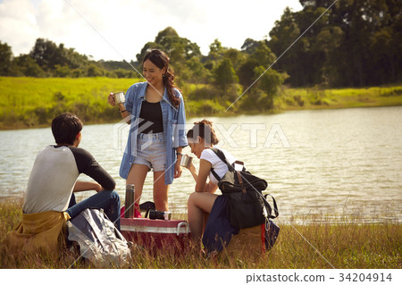 A group of friends is drinking coffee on the river bank. 34204914