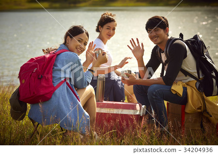 A group of friends is smiling and waving hand on the riverside A group of friends is smiling and waving hand on the riverside 34204936