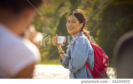 A young woman is smiling while drinking outside A young woman is smiling while drinking outside 34204950