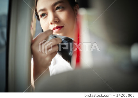 A young woman is holding the camera and smiling in the train 34205005