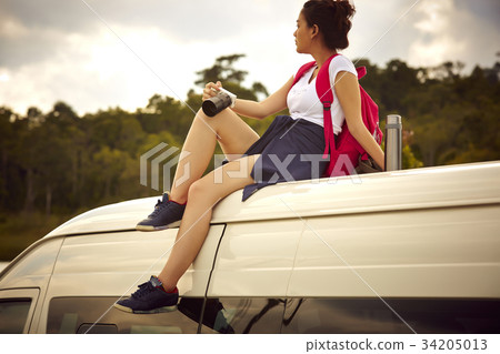 a young girl is sitting on truck's roof and holding a camera a young girl is sitting on truck's roof and holding a camera 34205013